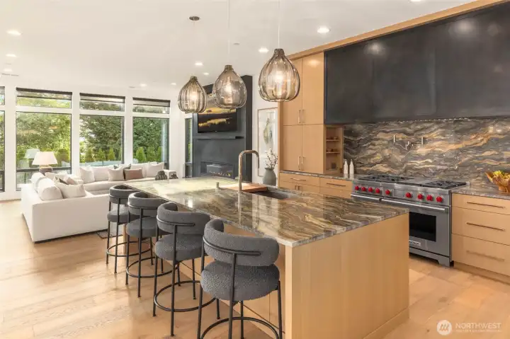 Chefs kitchen features stunning NW Inspired natural stone counters and backsplash, custom built blackened steel hood cover detail, and Wolf 48" Duel Fuel range with 6 burner stovetop and griddle, and double ovens