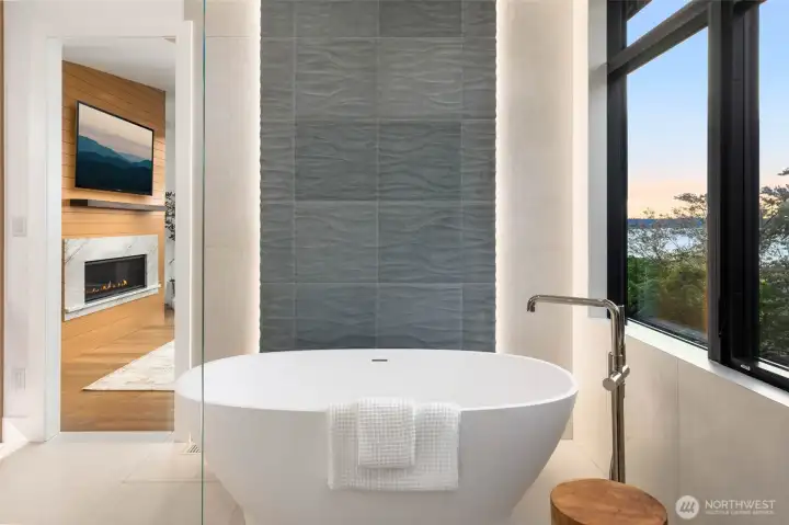 Gorgeous free standing sculptured stone soaking tub centered on backlit designer curated floor to ceiling tile feature wall
