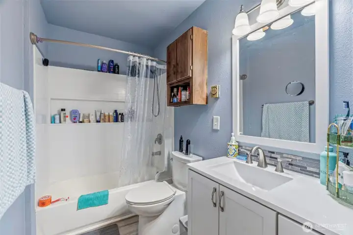Beautifully updated bathroom featuring new flooring,  brand-new cabinetry, fresh paint, and modern light fixtures.