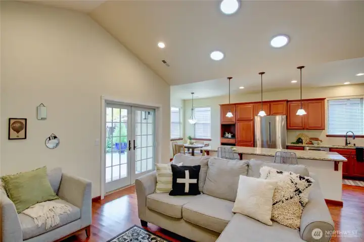 Great room looking towards kitchen, french doors to covered patio, hardwood floors, vaulted ceiling, eating bar and breakfast nook in the corner.