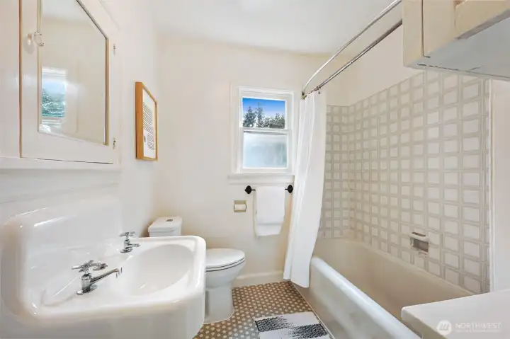 Full bathroom on main floor with tile floor and tub surround.