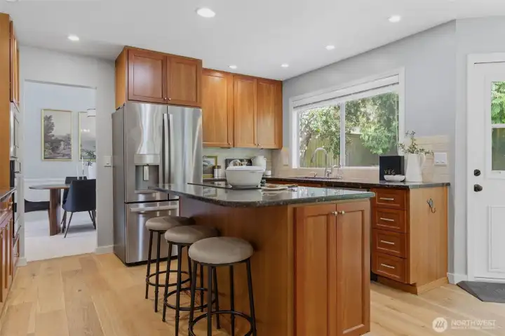 Open-concept kitchen features granite countertops, new appliances, engineered hardwood floors, pantry built-ins, and easy flow into the main living areas.