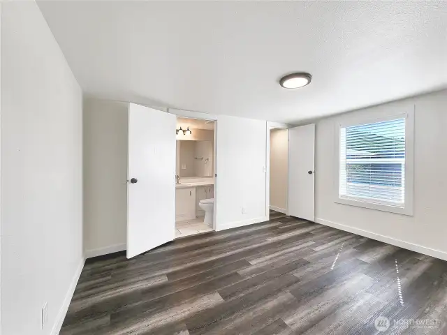 Wide angle view of primary bedroom with attached full bath and walk in closet