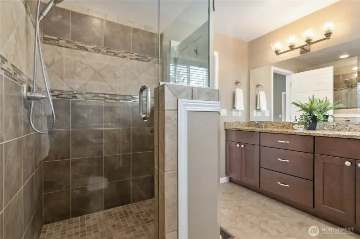 Walk-in custom tiled shower with glass door and half wall surround
