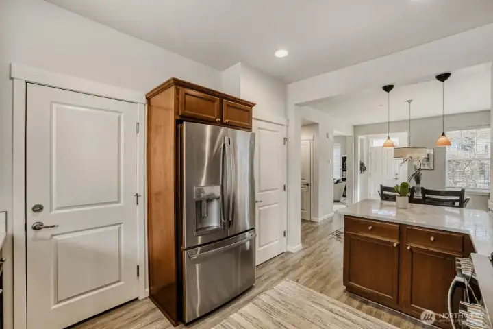 The newer stainless steel refrigerator is framed by doors into the garage and the pantry.
