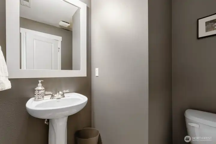 The powder room is freshly painted and features an attractive pedestal sink and LVP flooring.