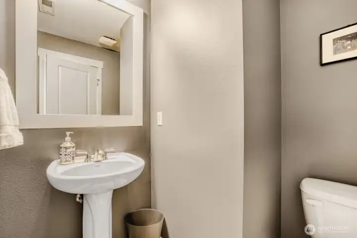 The powder room is freshly painted and features an attractive pedestal sink and LVP flooring.