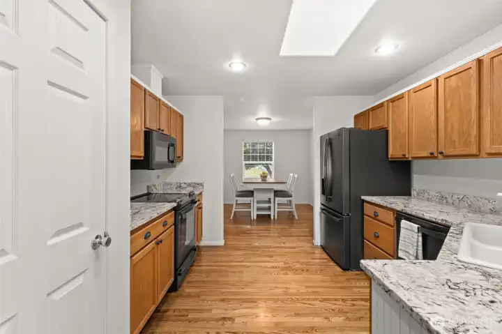 Well-designed kitchen positioned between the dining room and breakfast nook, creating functional gathering spaces with access to the covered back porch.