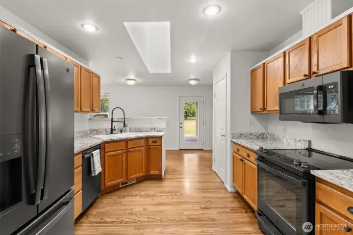 Beautifully designed kitchen featuring nearly new black stainless appliances, warm natural-tone granite countertops, pantry storage, and generous workspace for cooking and entertaining.