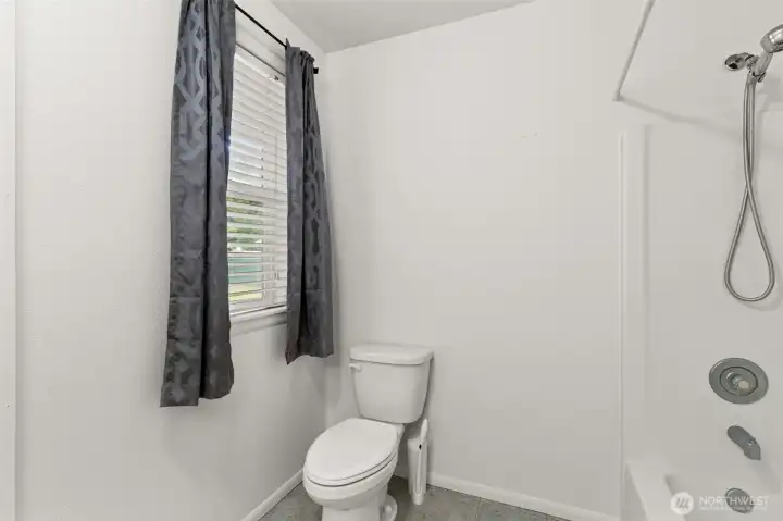 Primary bath with relaxing tub, window for natural light, and extended vanity area.