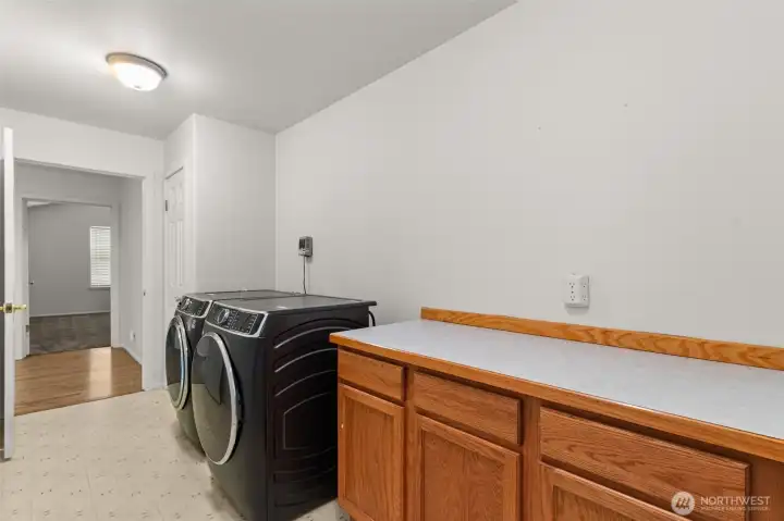 Large laundry room with newer front-load washer and dryer, folding counter, built-in storage, and extra room to keep everything organized.