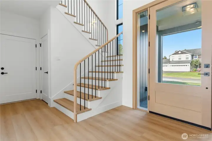 Bright entry with white oak handrail, sawtooth stringer stairs, and iron balusters.