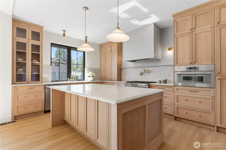 White rift cut oak cabinetry, quartz island, Thermador appliance package, and integrated plaster hood.