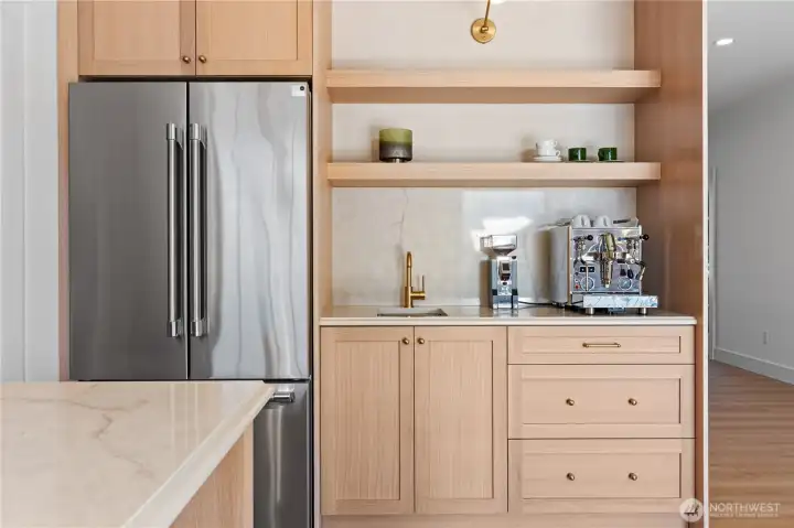Dedicated coffee bar with quartz backsplash, prep sink, and white oak floating shelves.