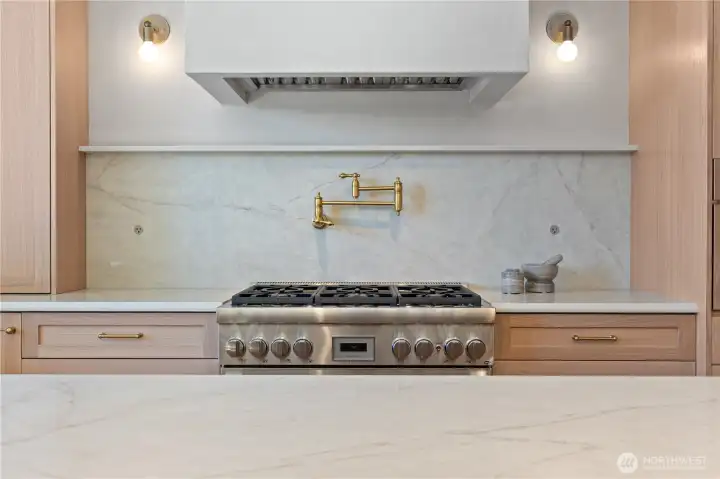 Thermador 36" gas range, brass pot filler, plaster hood, and quartz backsplash.