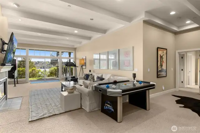 Spacious recreation room with high ceiling and view of Lake Washington and mountains.