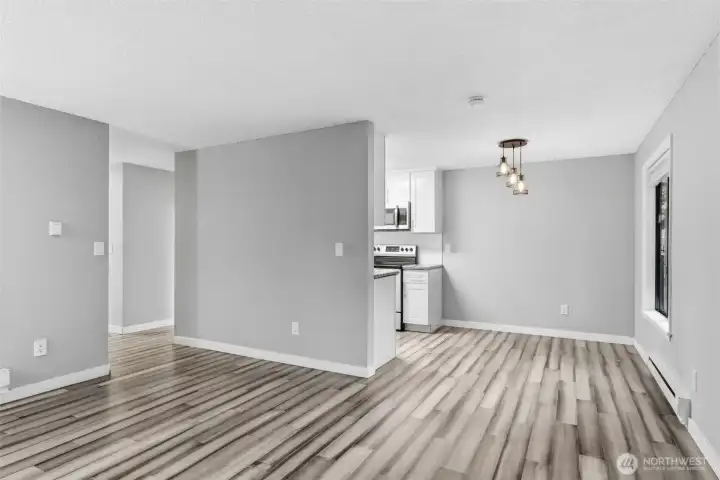 Another living room view showing the dining area and the hallway to the entry and bedrooms.