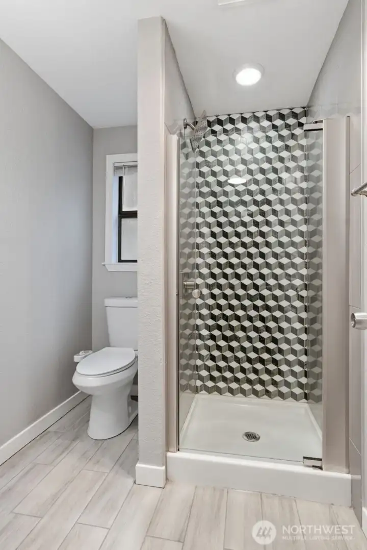 This bathroom also has lovely tile work on the walls and floors as well as a glass shower door.