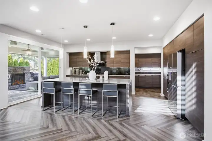 A striking quartz island anchors the chef’s kitchen, seamlessly connecting to both the great room and covered outdoor living beyond. Grand butler's pantry is beyond