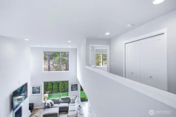 An open upper landing overlooks the dramatic great room below, maintaining a sense of light and connection throughout.