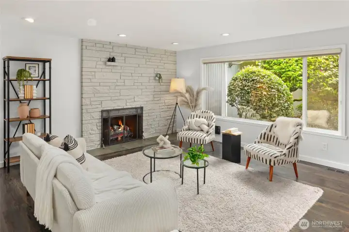 Light filled living room with wood burning fireplace open to dining room and kitchen.