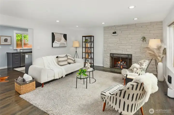 Light filled living room with wood burning fireplace open to dining room and kitchen.