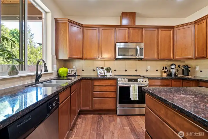 Beautiful granite slab countertops, kitchen window over sink looking into back yard.