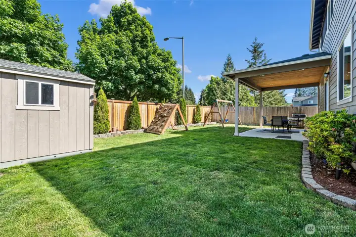 Spacious, flat, fully fenced back yard with storage shed.
