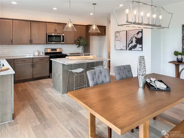 Quartz counters, modern black light fixtures, single basin undermount sink, stainless steel appliances, gas stove, hood vent above range, laminate flooring throughout main entry, kitchen and living spaces.  Walk in pantry. *Photos not of actual home - same floor plan in a different community*