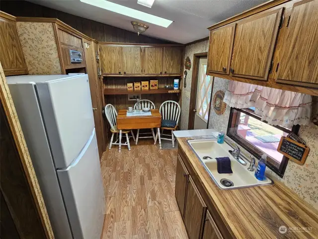 Back door into the kitchen with eating area, new refrigerator and lots of storage.