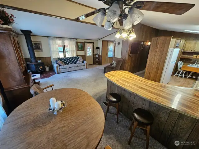 Dining area with ceiling fan and into the great room with wood burning stove.