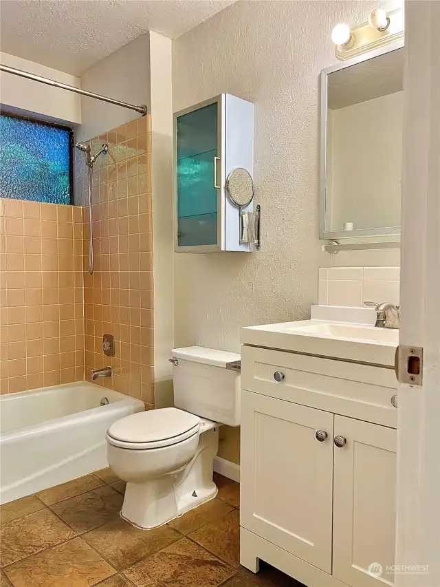 The full size guest bath is located by the utility room.  The shower surround is tiled with attractive sunny yellow tile.