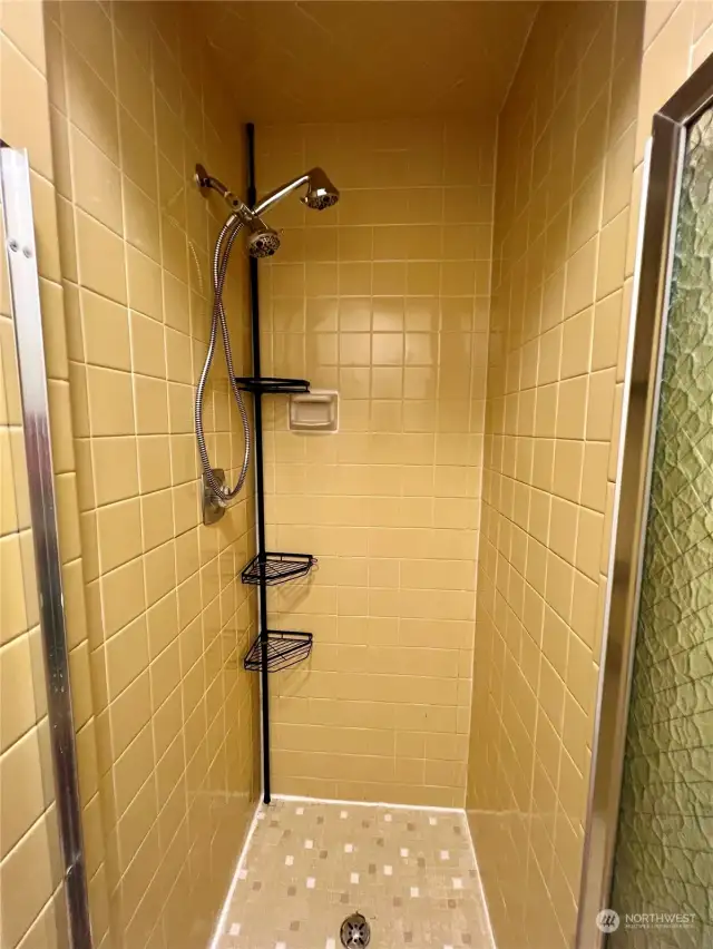 The primary shower is fully tiled with pretty yellow tile.