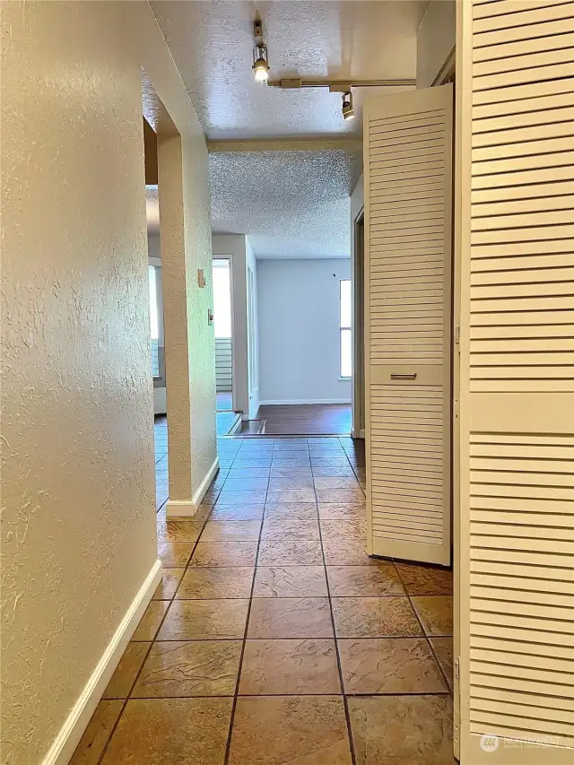 From the entry, when you turn left this hallway leads to the kitchen and living areas. The coat closet, hallway to guest bath and utility room, and large pantry are on the right side.