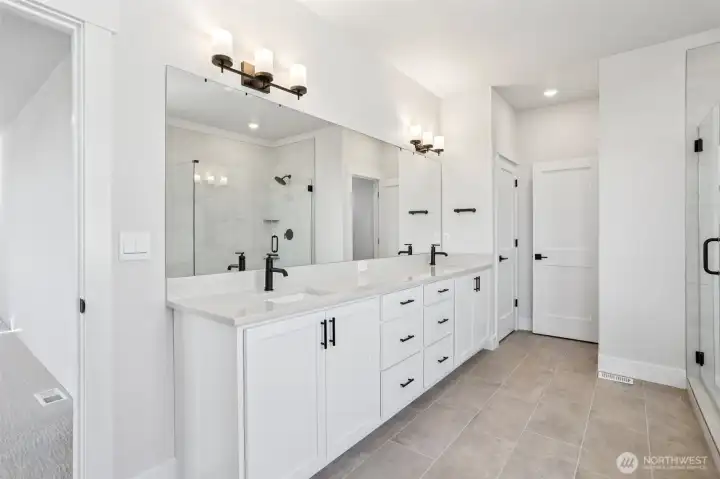 Dual vanity with extensive cabinetry plus linen closet highlights the primary bathroom.