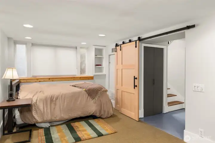 An additional bedroom is found at the bottom of the stairs - suited with barn doors for an airy space with privacy accessible at any point