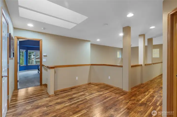 The upper-level landing features an elegant open-rail banister that maintains the home’s airy, connected feel. This spacious transition area offers easy access to the private quarters while overlooking the grand architectural details of the main floor.