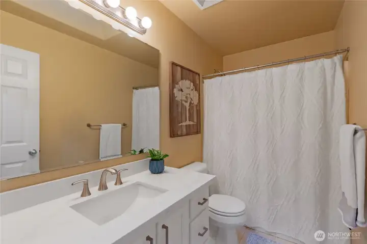 The secondary upstairs bathroom is thoughtfully designed with a spacious vanity, sleek chrome fixtures, and a clean, modern aesthetic. Serving the guest bedrooms, it features a full tub-and-shower combination and easy-to-maintain flooring.