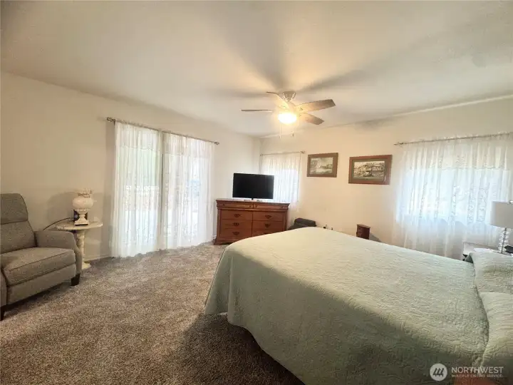 Primary bedroom features sliding doors that open to a comfortable outdoor seating area, perfect for relaxation and enjoying the fresh air.