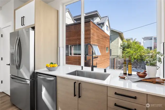 Sunlit kitchen with oversized windows, featuring high-end appliances and contemporary design elements.