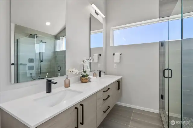 Spa-like bathroom featuring dual sinks, a spacious glass shower, and modern fixtures.