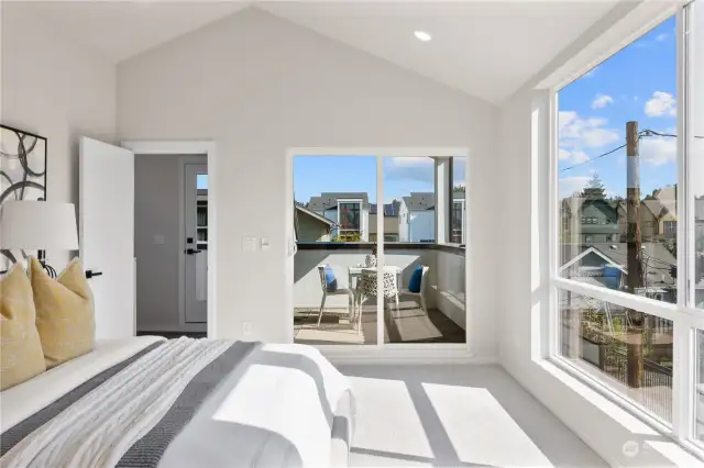 A master bedroom retreat with a vaulted ceiling, natural light, and access to a private balcony for a peaceful escape.