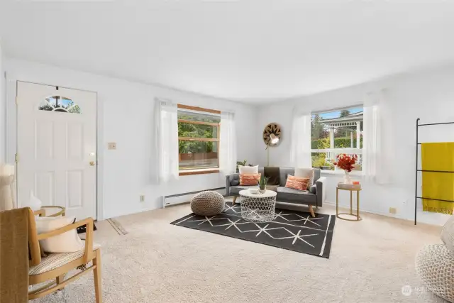 The living room is bright and welcoming, featuring large windows that fill the space with natural light.