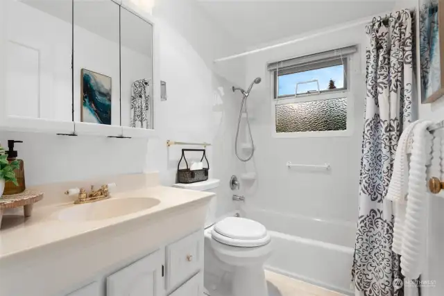 The bathroom features a tranquil space with a window above the tub, allowing natural light to brighten the room.