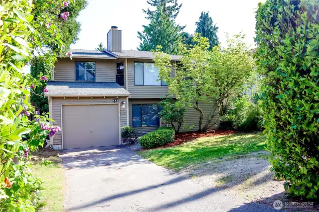 View as you pull in to the driveway. Enter house from front door or through 1-car garage, or follow the path on the left side around to the backyard.