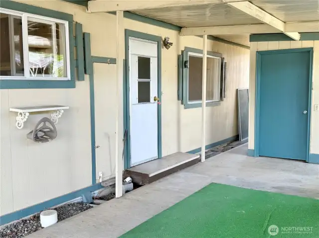 Close up of the carport with access to the utility room, backyard and storage unit.