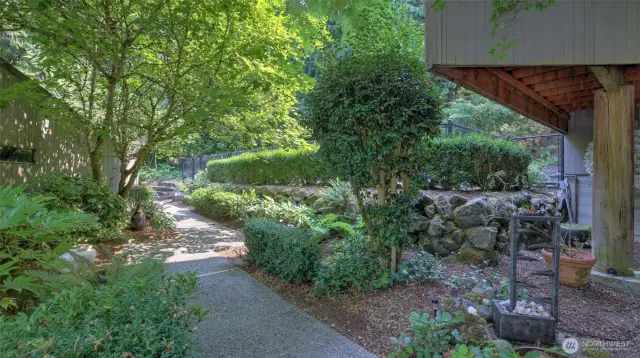 Stroll along a peaceful garden pathway surrounded by lush landscaping and mature trees.