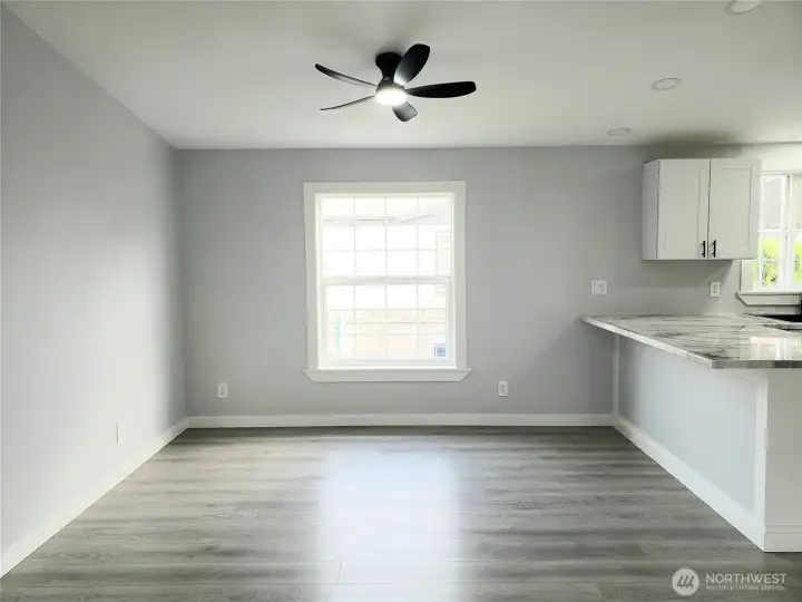 A View of the Dining Room and Kitchen showing the Breakfast Eating Bar from the Huge Living Room with Cathedral Ceilings, New Paint Trim and Vinyl Plank Flooring.