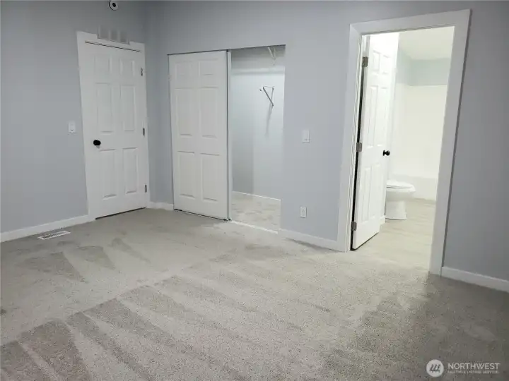 A Different View of the Primary Master Bedroom Showing Cathedral Ceilings, All New Paint, Trim and Carpeting, Looking into the Huge Walk In Closet and Primary Bathroom.