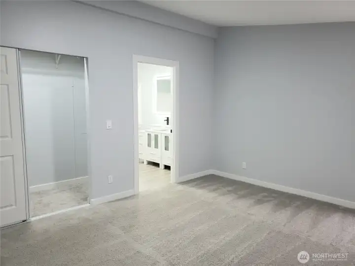 A Different View of the Primary Master Bedroom Showing Cathedral Ceilings, All New Paint, Trim and Carpeting, Looking into the Huge Walk In Closet and Primary Bathroom.
